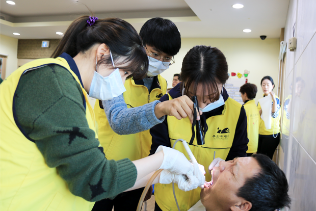중증장애인 치과진료를 돕고 있는 김성재 학생(가운데)