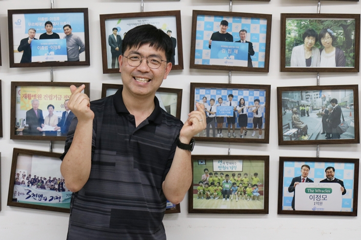 푸르메재단 벽에 걸린 제자들의 사진 옆에 선 박성우 교사