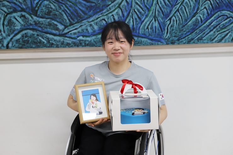 발달장애인 팬이 그려준 초상화와 이를 담은 케이크를 선물 받고 활짝 웃는 김윤지 선수