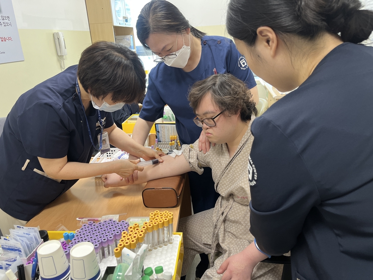 푸르메재단이 진행한 장애가족 건강검진 지원사업에서 의료진의 도움을 받으며 안정적으로 채혈하고 있는 발달장애인 모습