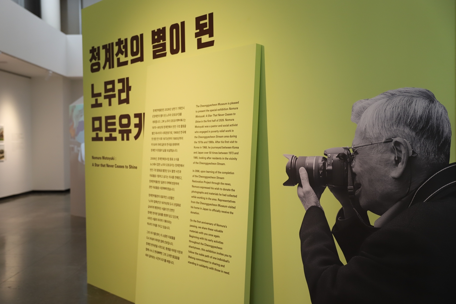 청계천의 별이 된 노무라 모토유키 사진전 현장. 카메라를 손에 든 노무라 모토유키 씨의 모습을 담은 사진이 입구에서 관람객을 맞고 있다. 사진전은 오는 10월 11일(일)까지 열린다.