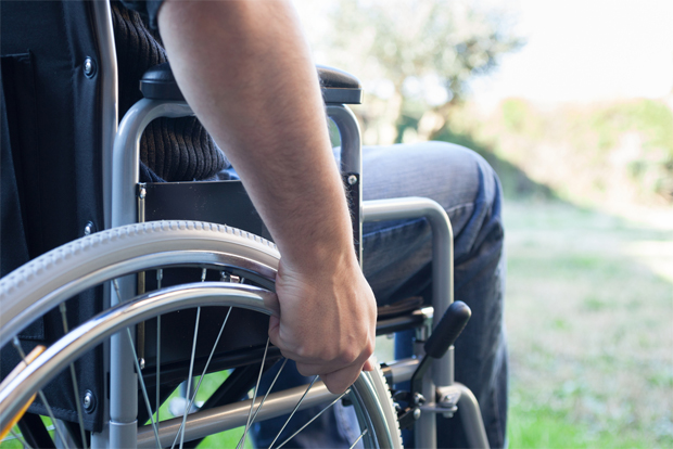 휠체어를 양 팔의 힘으로 움직이고 있는 장애인